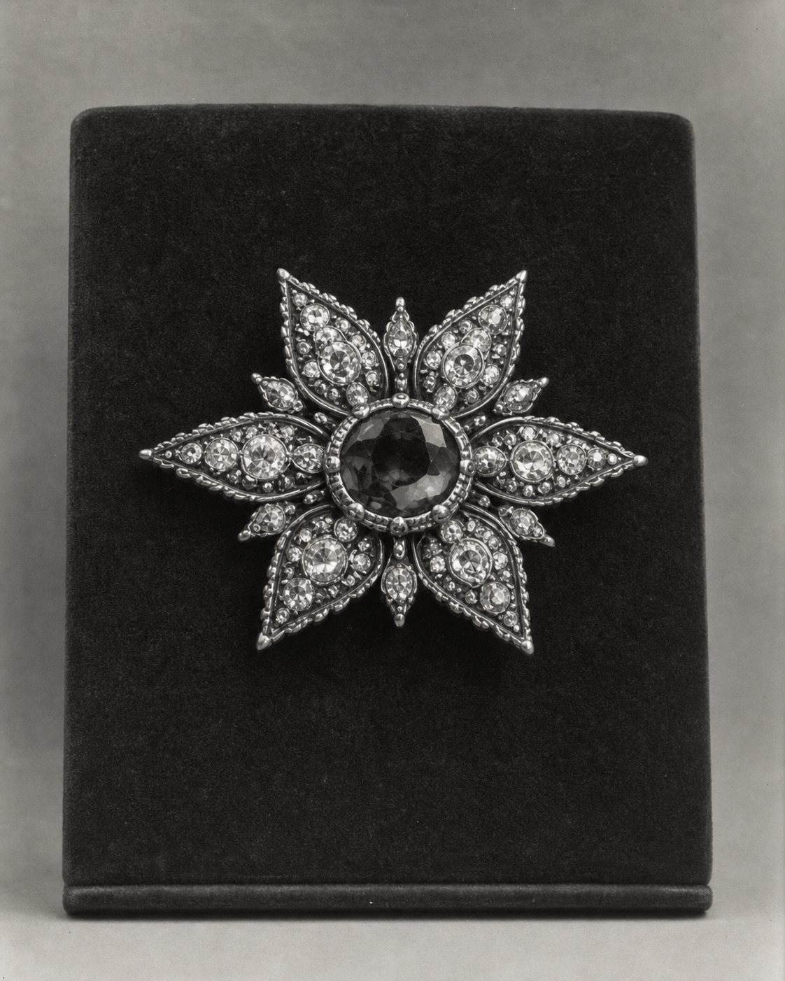 Black and white photograph of an ornate star-shaped jewel against a dark background.